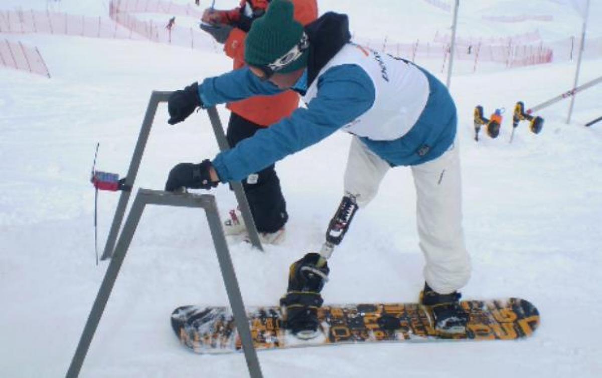 A picture of a man with a prosthesis practising snowboard