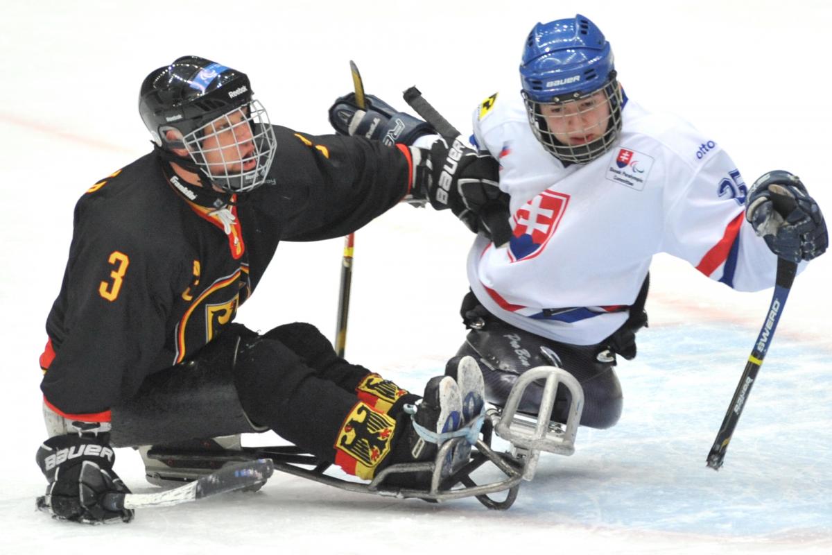 A picture of two men in sledge playing ice hockey