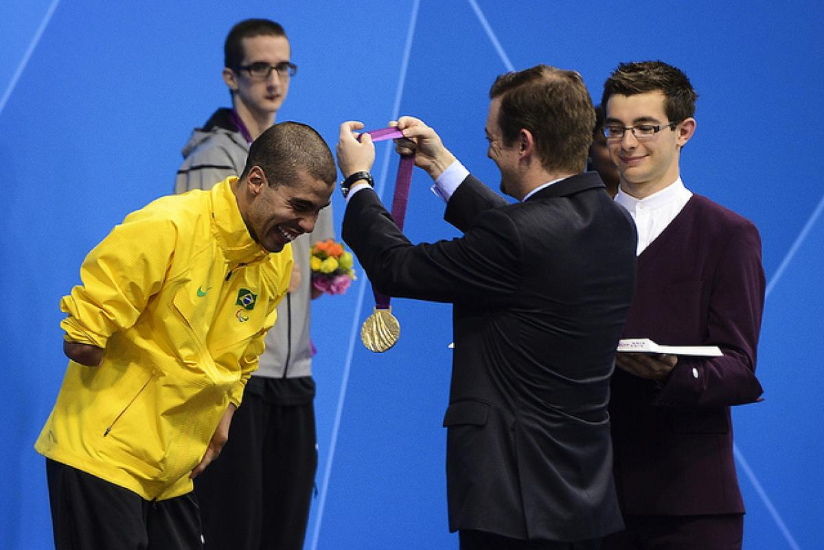A picture of a man giving a medal to an athlete during a medal ceremony