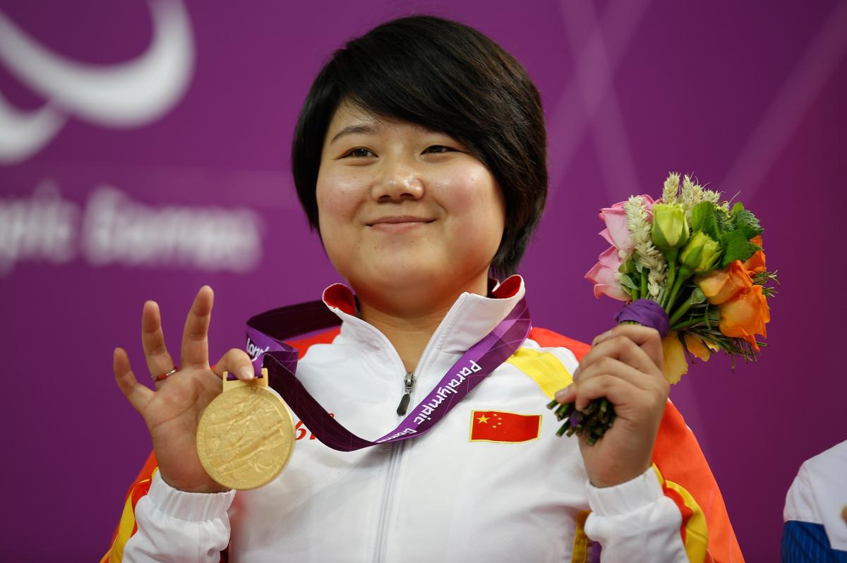 A picture of a woman on a podium with a medal around her neck