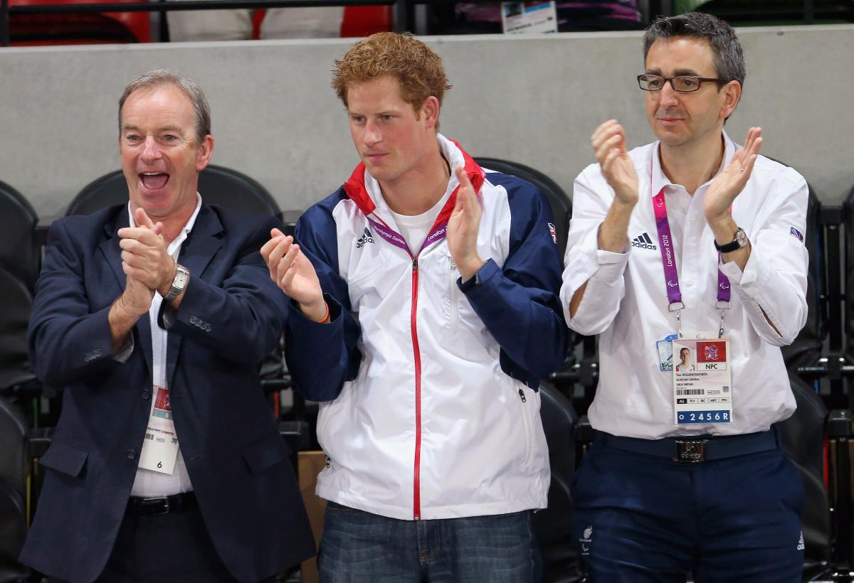 A picture of 3 men standing and applauding 