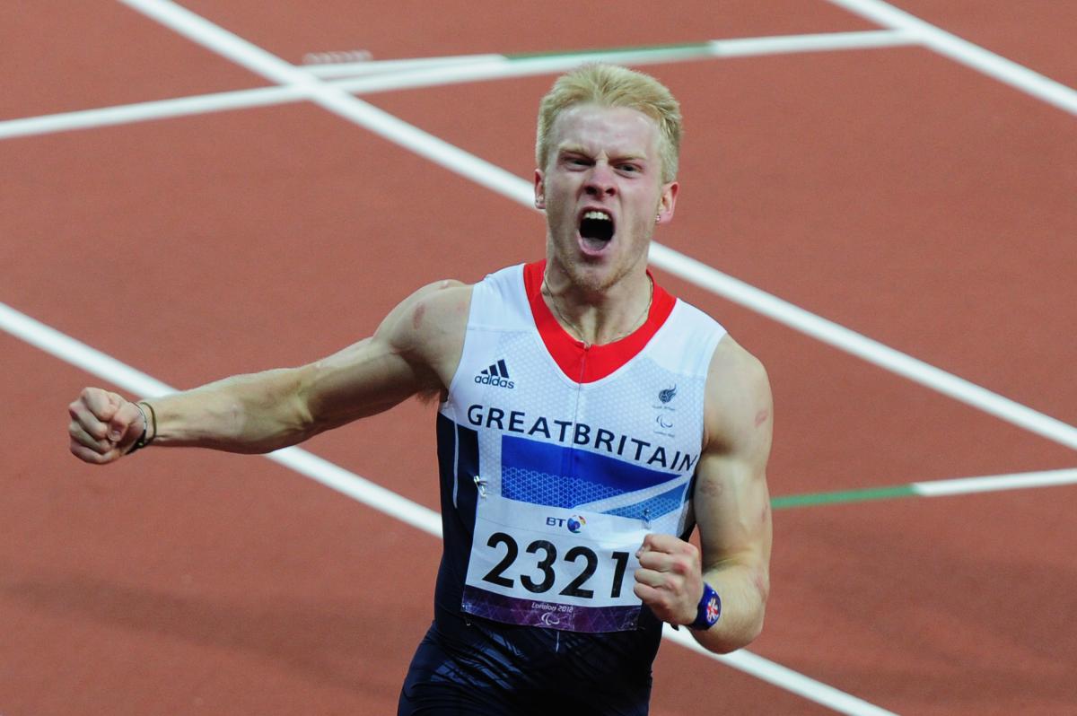 A picture of a man crossing a finish line during an athletics race and celebrating his victory