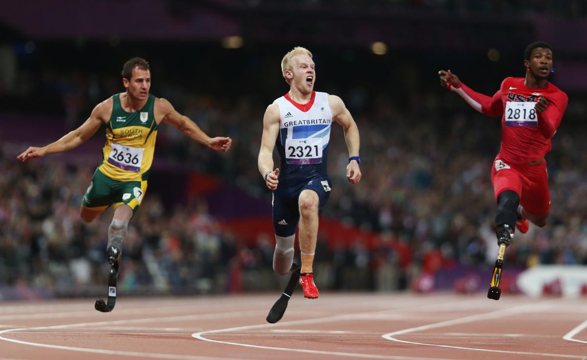 A picture of 3 men crossing the finish line during an athletics race