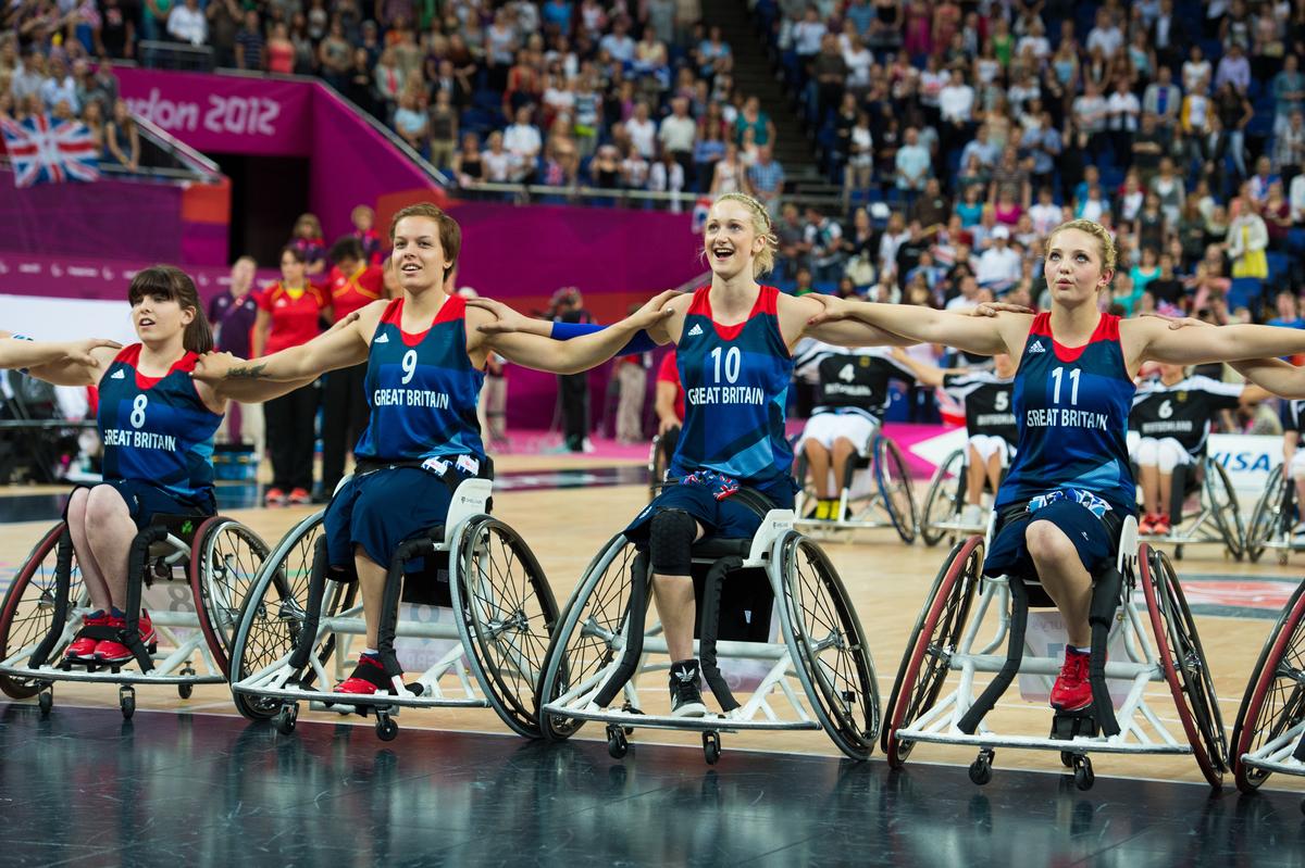 A picture of women in wheelchair posing for a group picture during a wheelchair basketball match