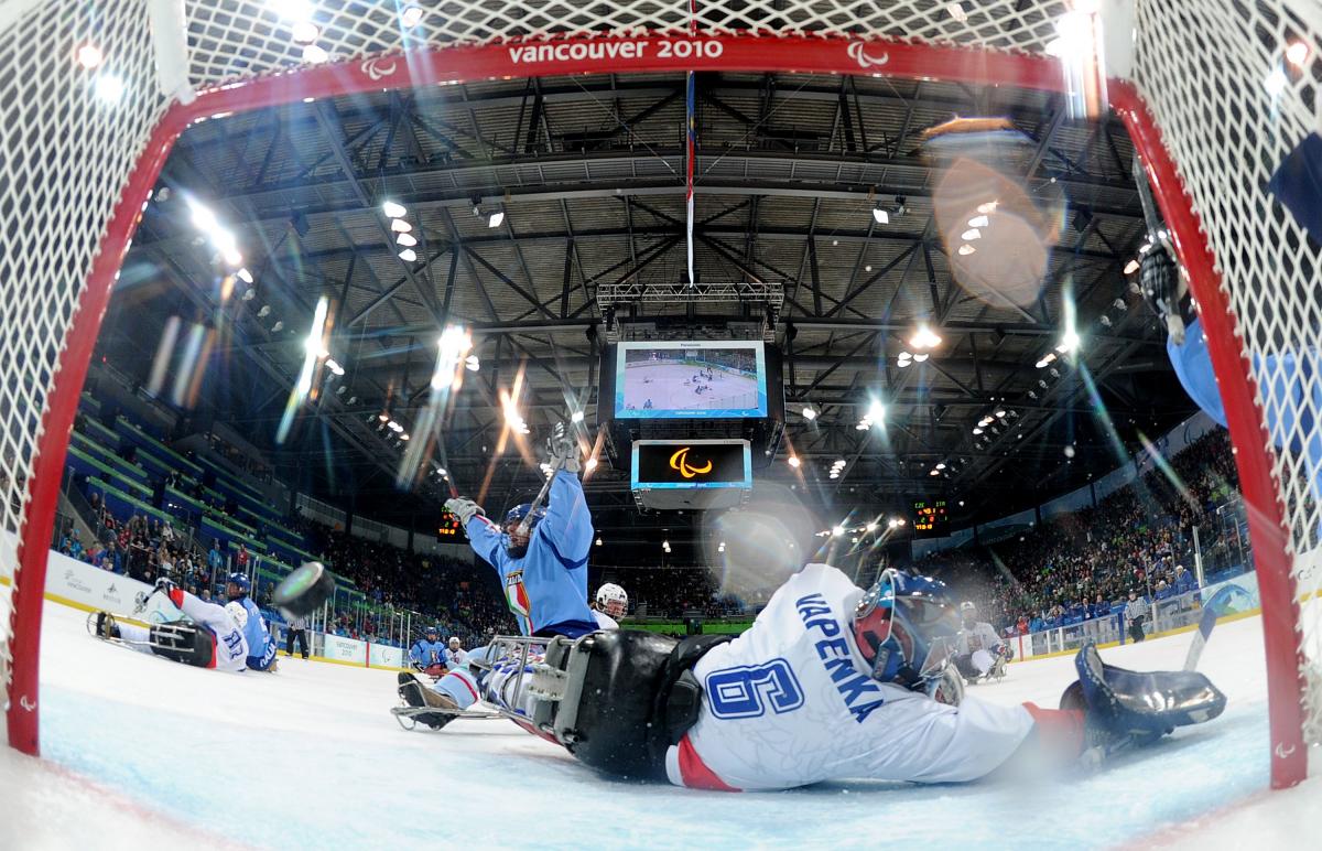 A picture of a man in a sledge celebrating his goal during an ice sledge hockey match.
