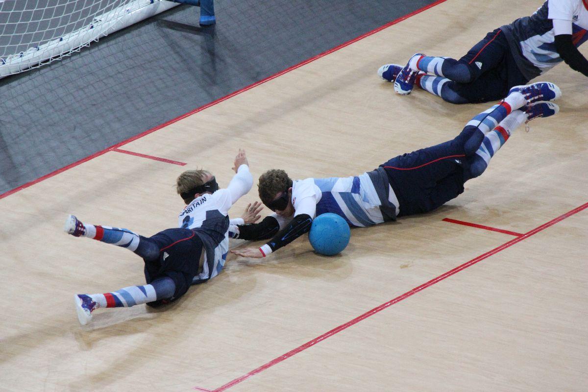 A picture of three blind men laying on the ground and trying to stop a ball