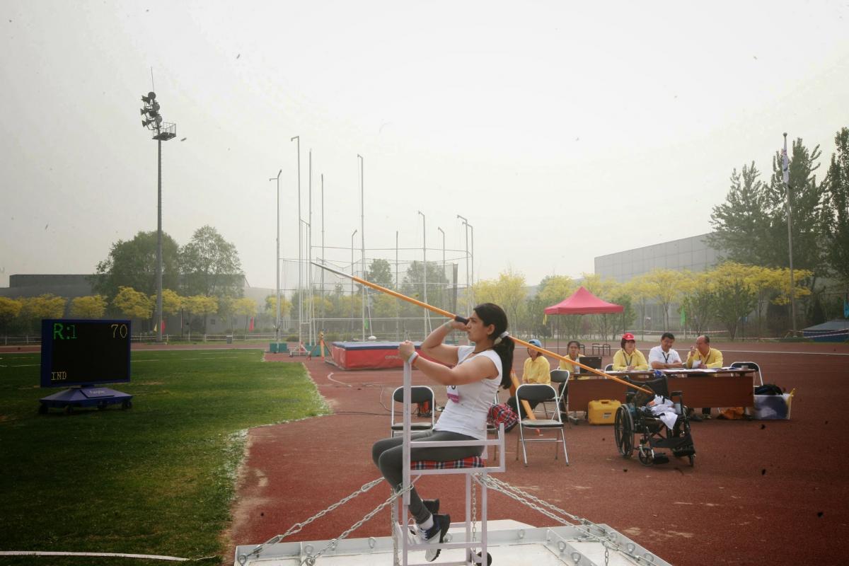 Female athlete throws the javelin from a seated position