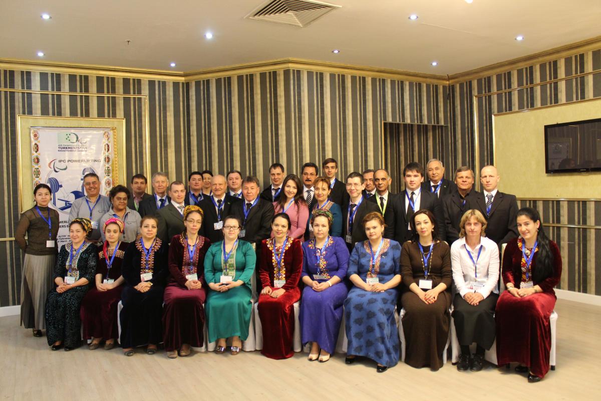 Participants of the seminars for powerlifting referees and classifiers in Turkmenistan 34 people sit and stand in front on a wall for a group picture
