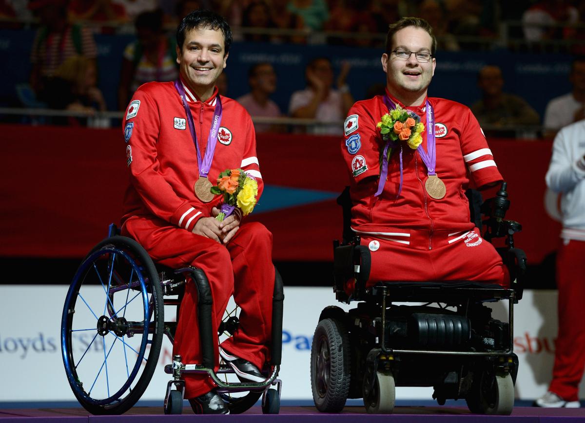 Marco Dispaltro Two boccia player sit in the wheelchairs with their medals around their neck.
