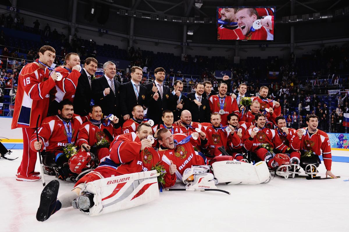 The entire Russian ice sledge hockey team poses with their medals on the ice facing the camera. 