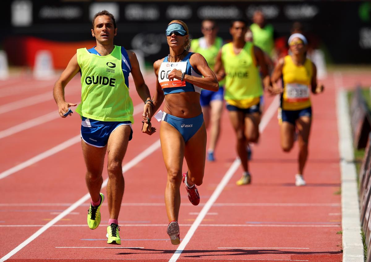 A visually impaired women and her guide running on the track of a stadium