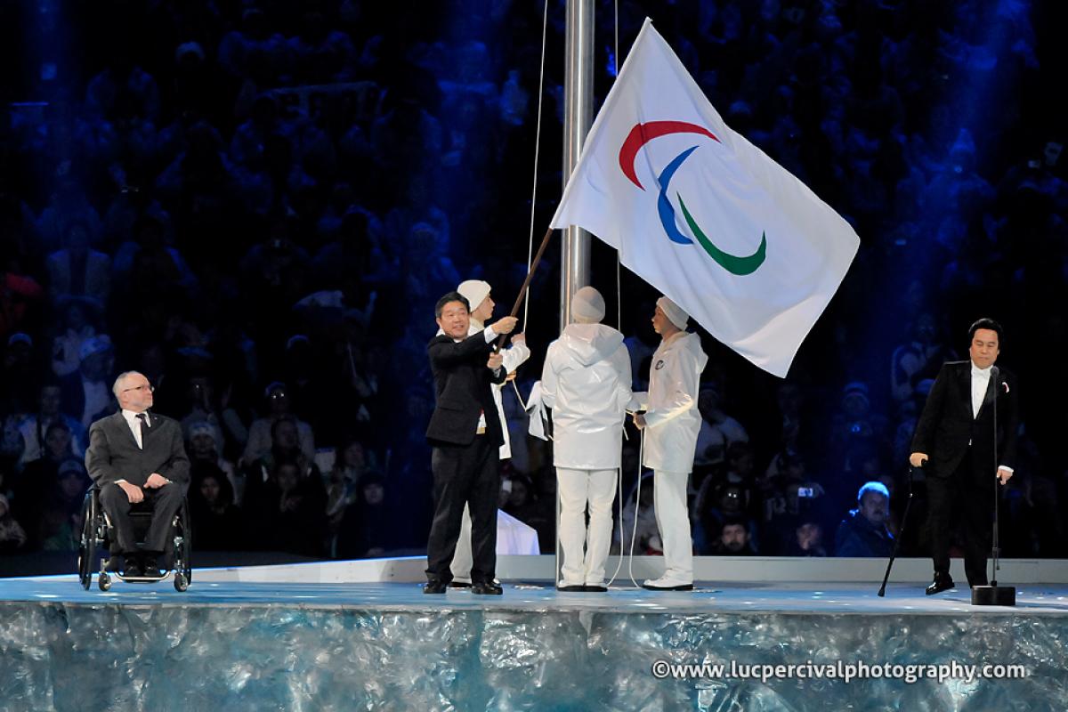 A man waves the Paralympic flag on stage