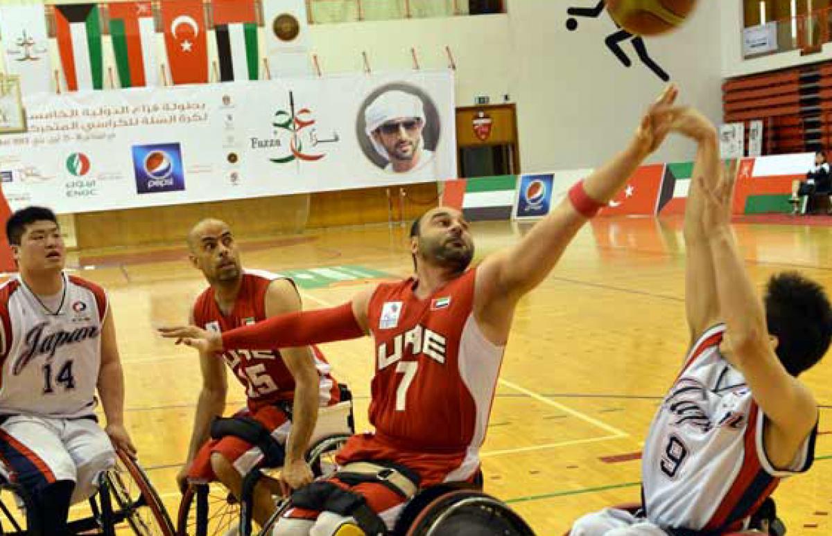 A man in a wheelchair shoots a basketball layup. 