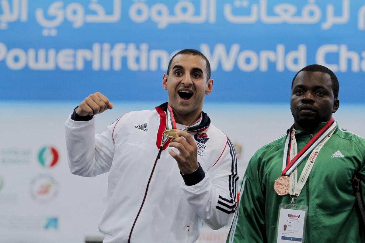 An athlete poses showing his gold medal.