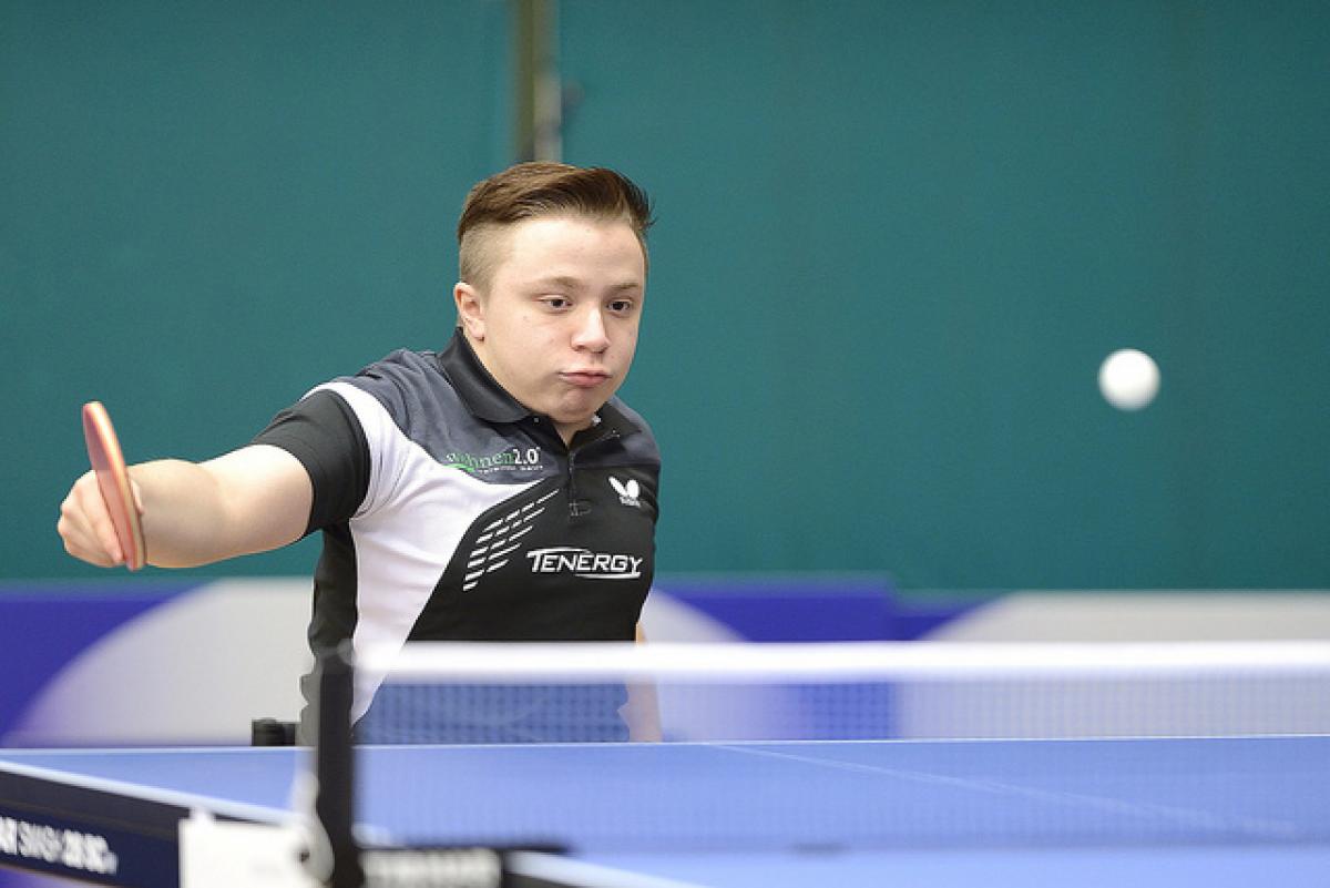 An athlete hits a table tennis ball. 