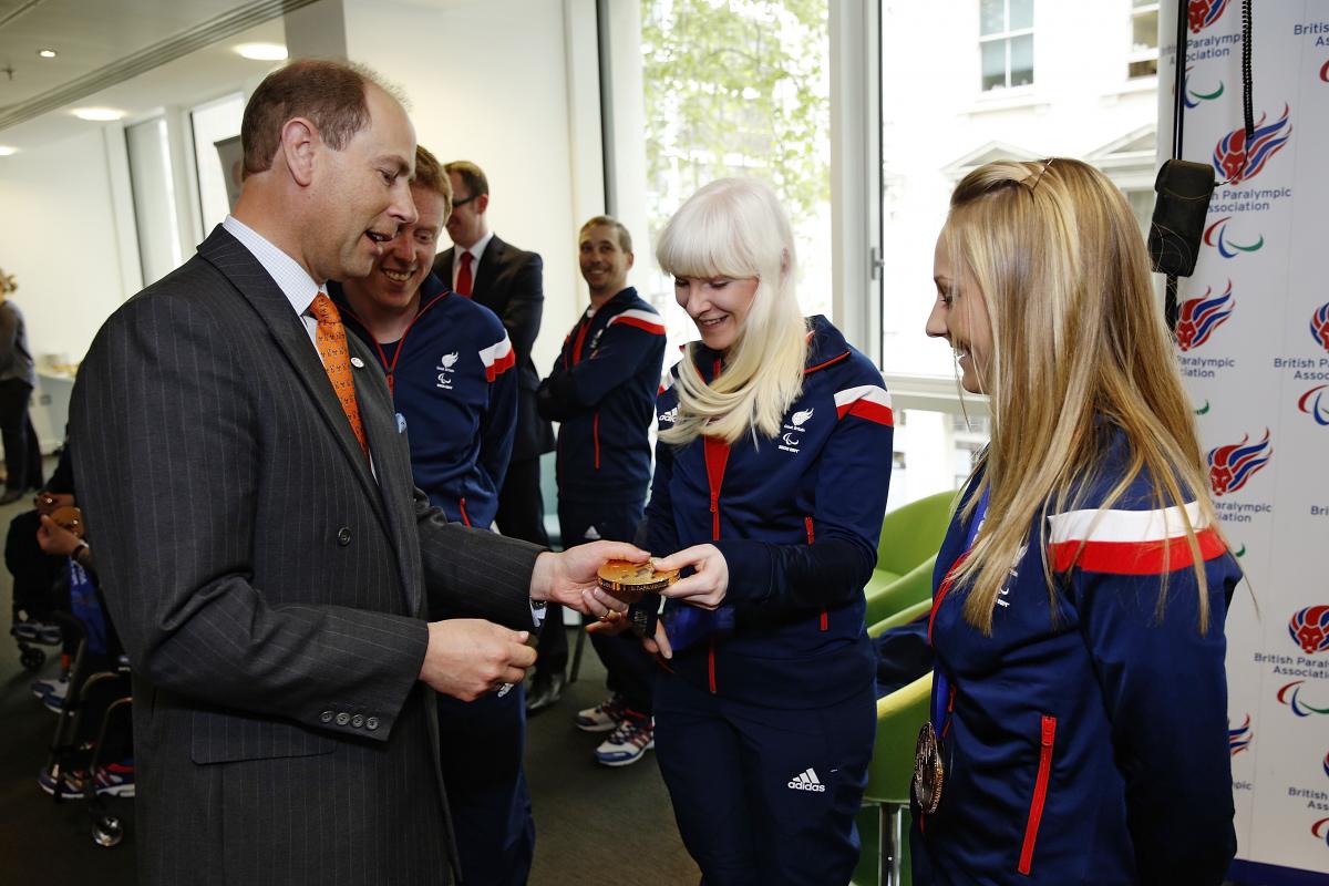 A man reaches out to look at Kelly Gallagher's Sochi 2014 gold medal.
