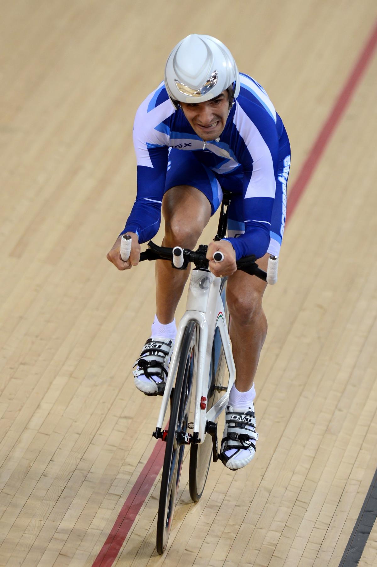 A man cycles straight ahead on a track.