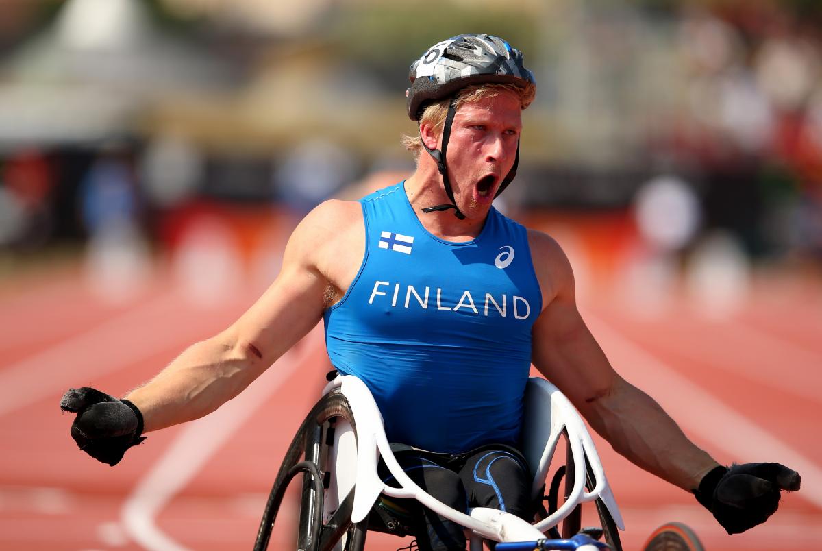 An wheelchair racer shouts out after crossing the finish line in first place.