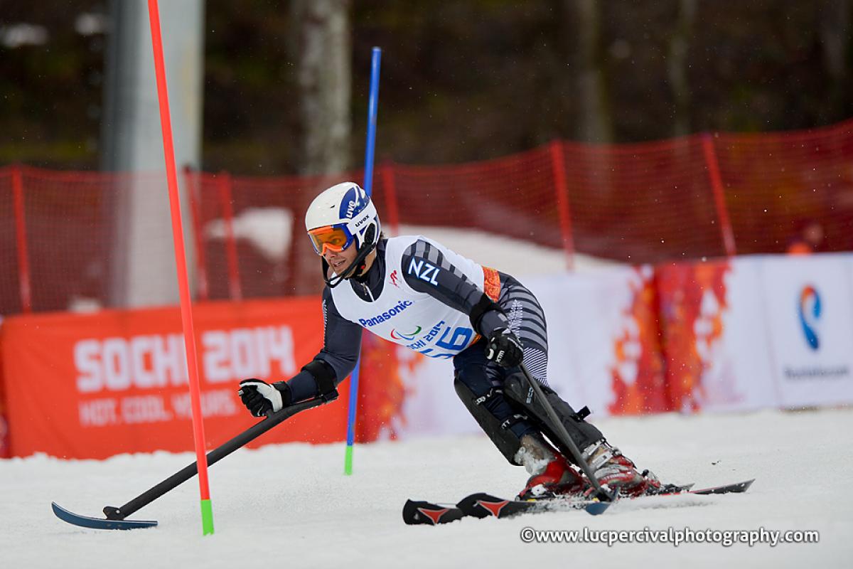 Skiing man curving around some slalom poles