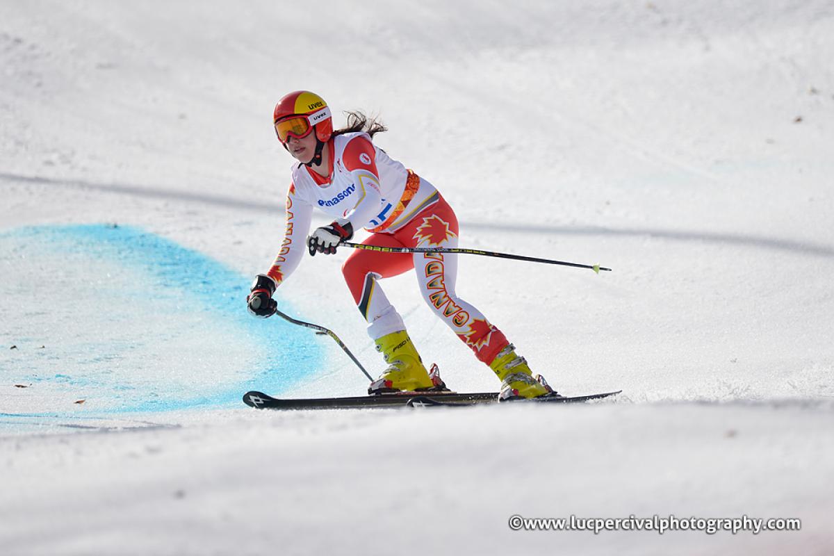 Skier in orange and white ski suit, skis at speed down slope