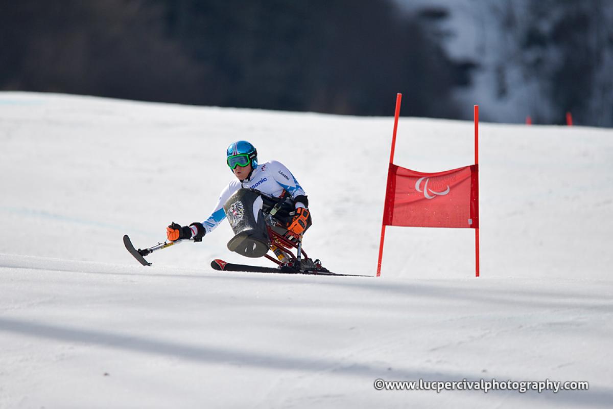 Claudia Loesch - Sochi 2014 Winter Paralympic Games Woman in sit ski on a slope passing a gate