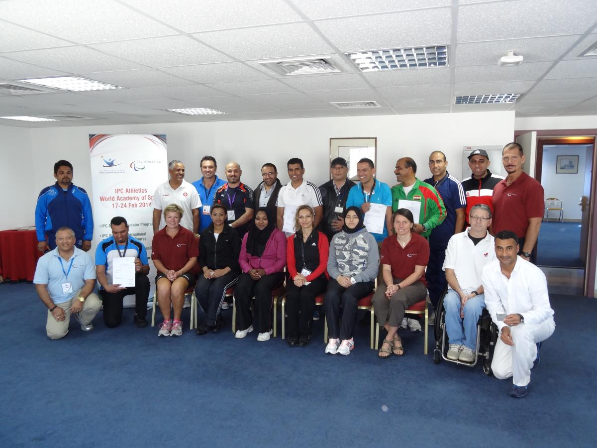 Group shot of men in women in room with blue floor anr white walls.