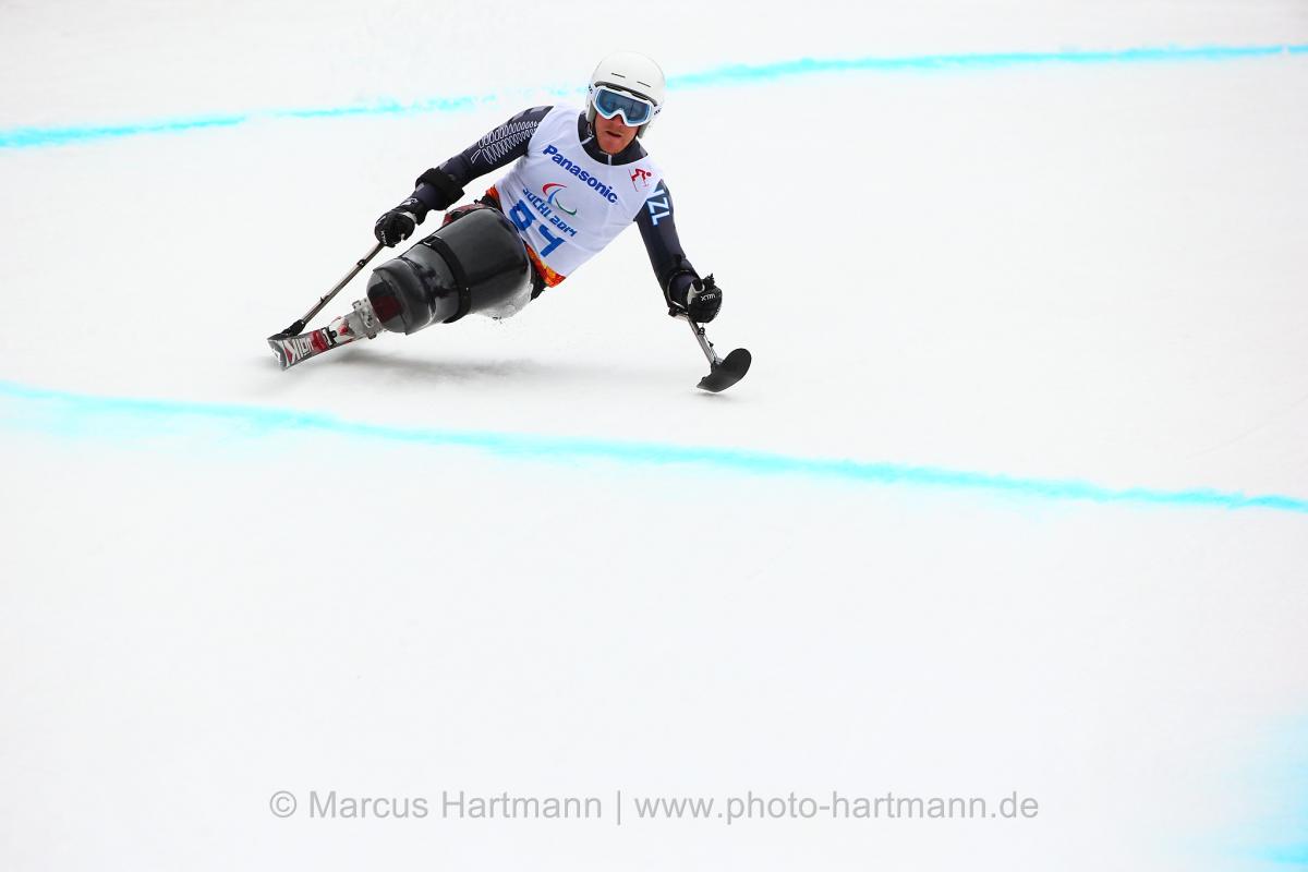 Sit skier going down a slope leans to his left