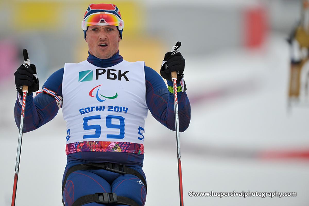 Close up of torso of sit skier driving forward through the snow with ski poles