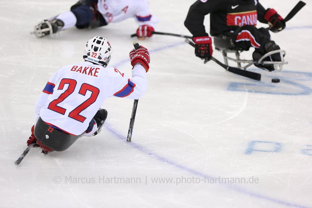 two Para ice hockey players close in on the puck