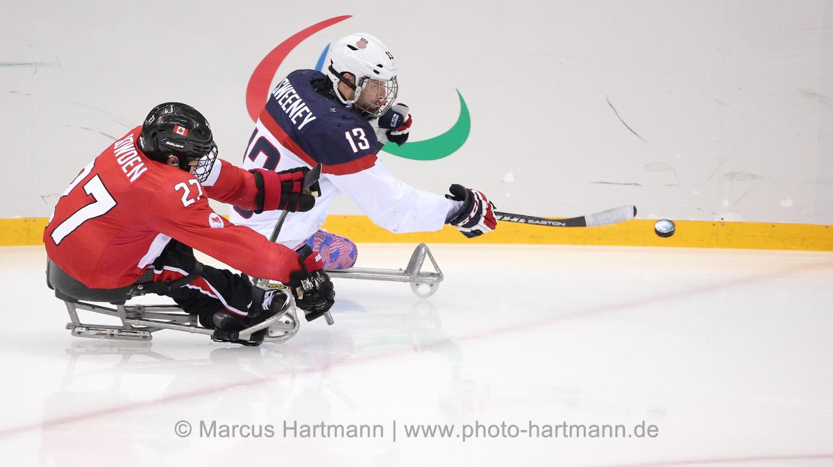 Canads's Brad Bowden and the USA's Josh Sweeney race for the puck during Sochi 2014.
