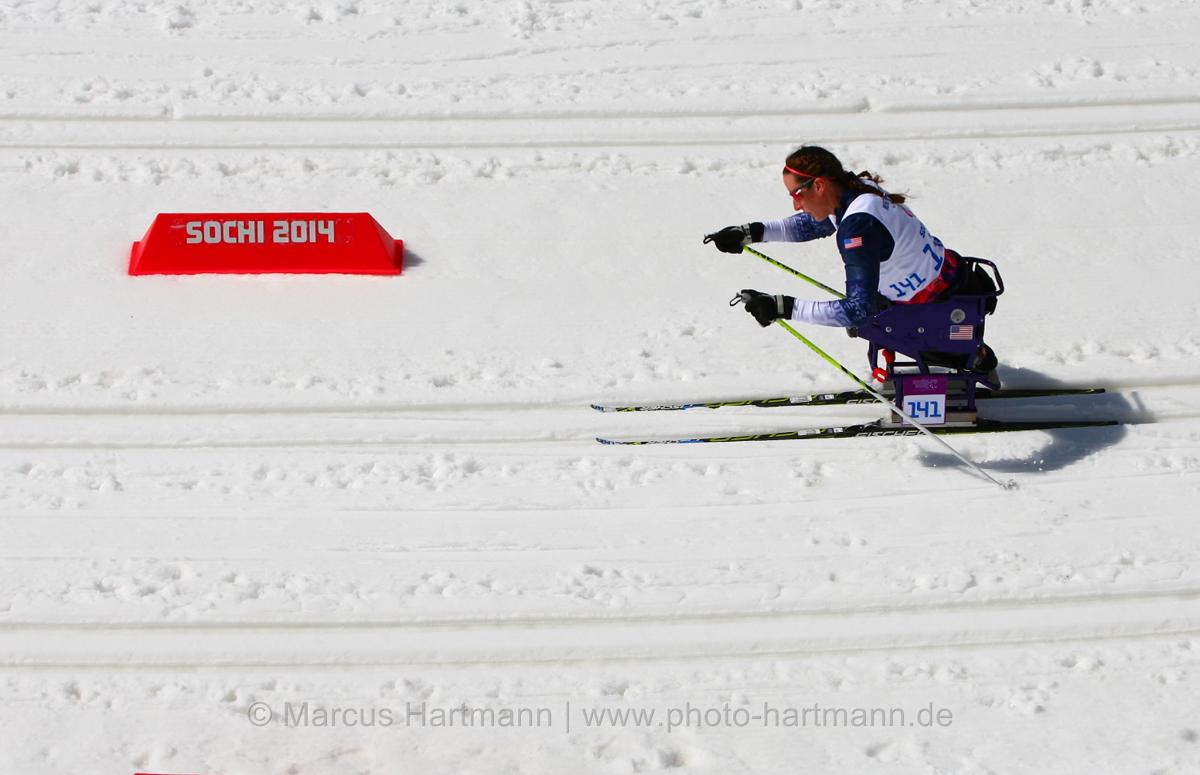 Women in sit ski on a cross country track