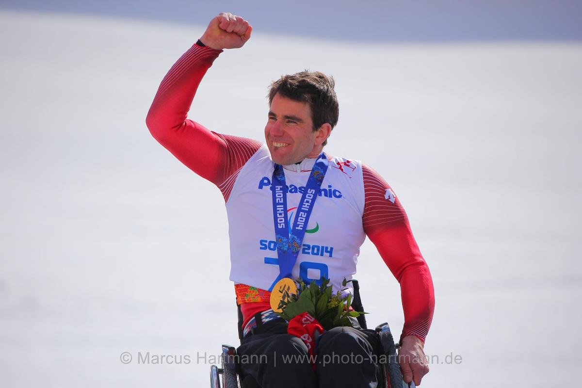 Upper body of man in wheelchair celebrating with medal around his neck