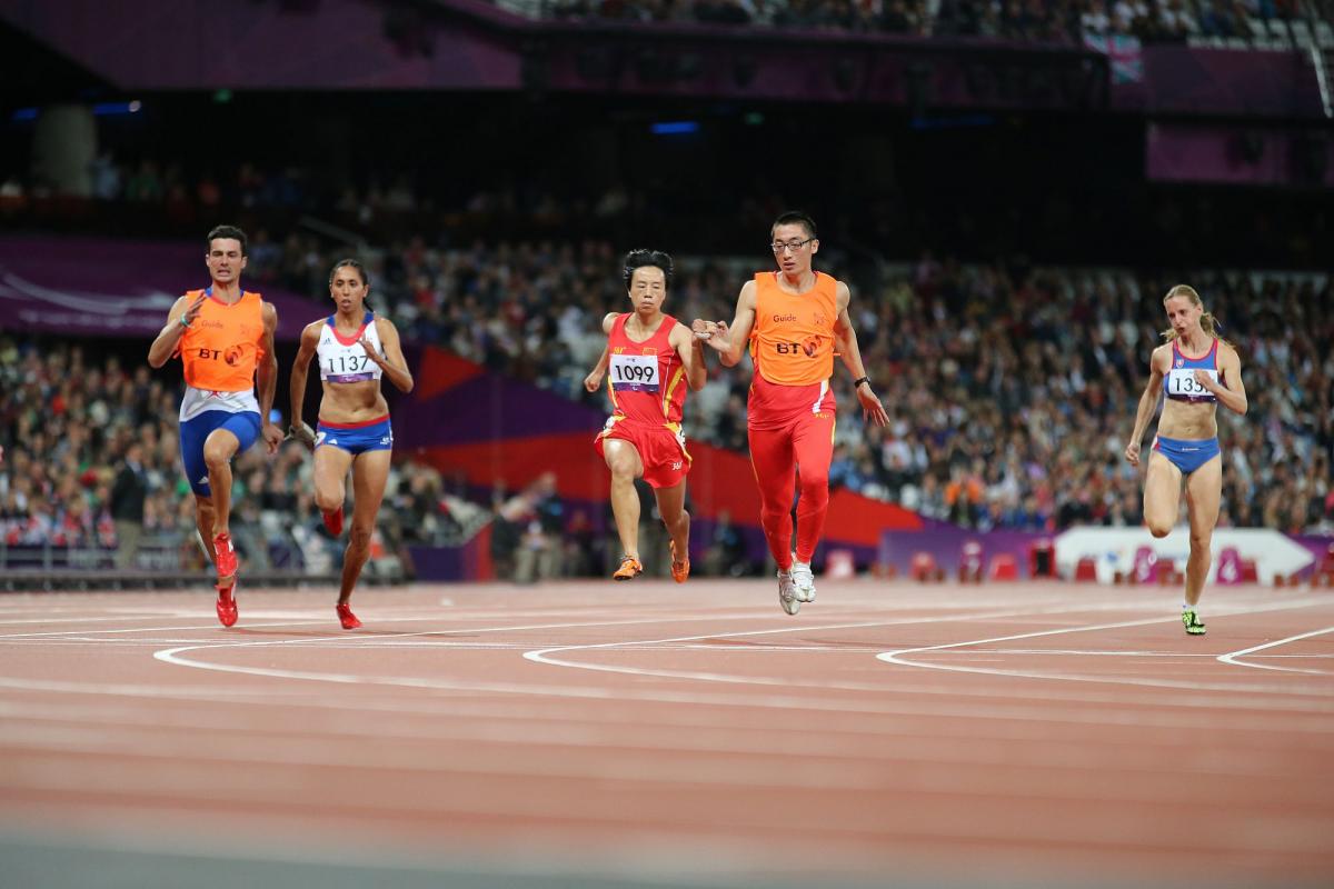 Female runners with guides on a track running