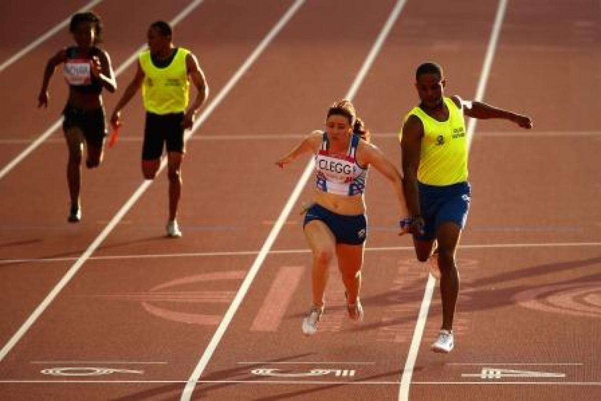 Two runners cross the finish line in a stadium