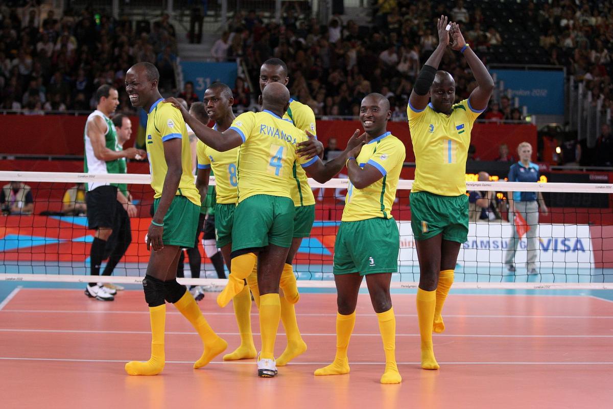 Rwanda - Sitting Volleyball - London 2012 Paralympic Games Six men celebrating on a volleyball field.