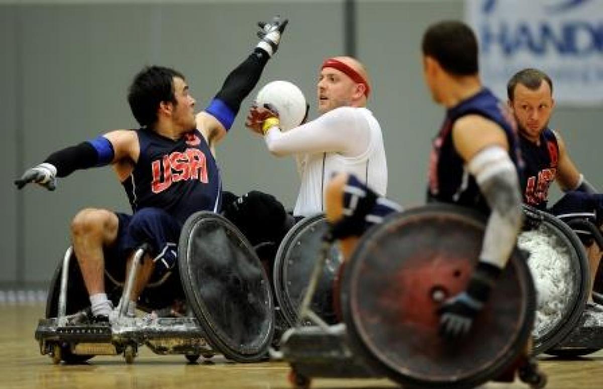 Two wheelchair rugby players fight for the ball on the field of play