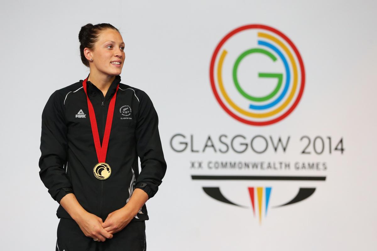 Sophie Pascoe at Glasgow 2014 Women in training suit stand in front of a wall with the Glasgow 2014 logo