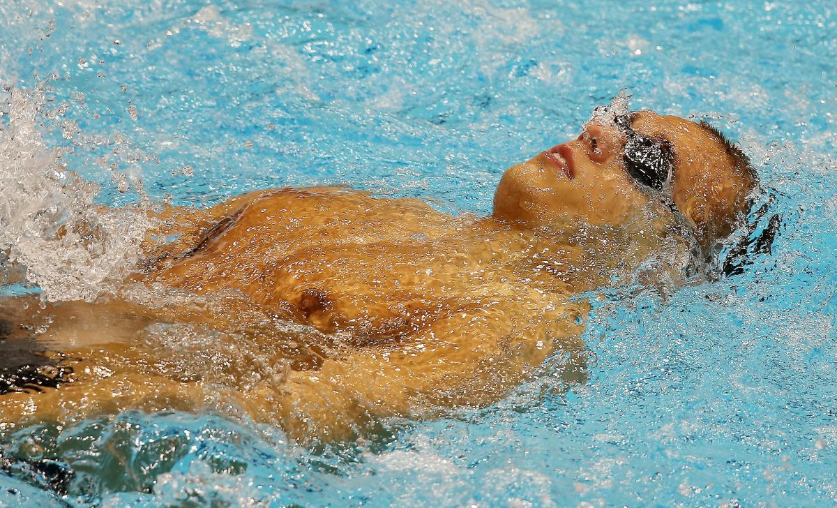 A swimmer wearing goggles laid on his back in the water at the start of a race.