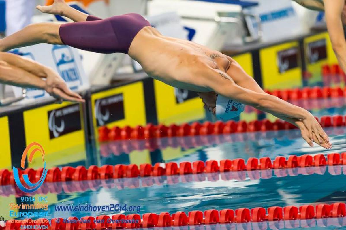 A swimmer diving into the pool at the start of a race.