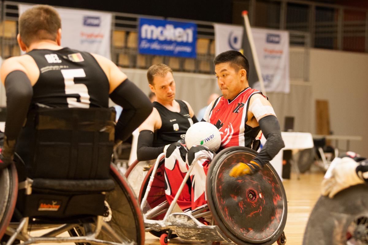 Man in a wheelchair with a ball in his lap going forward.