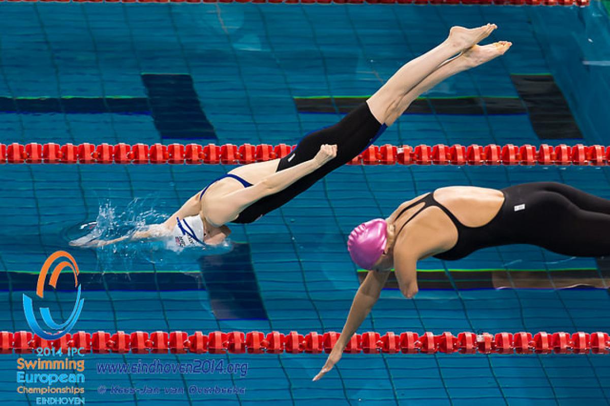 Two female athletes dive into the pool at the 2014 IPC Swimming European Championships