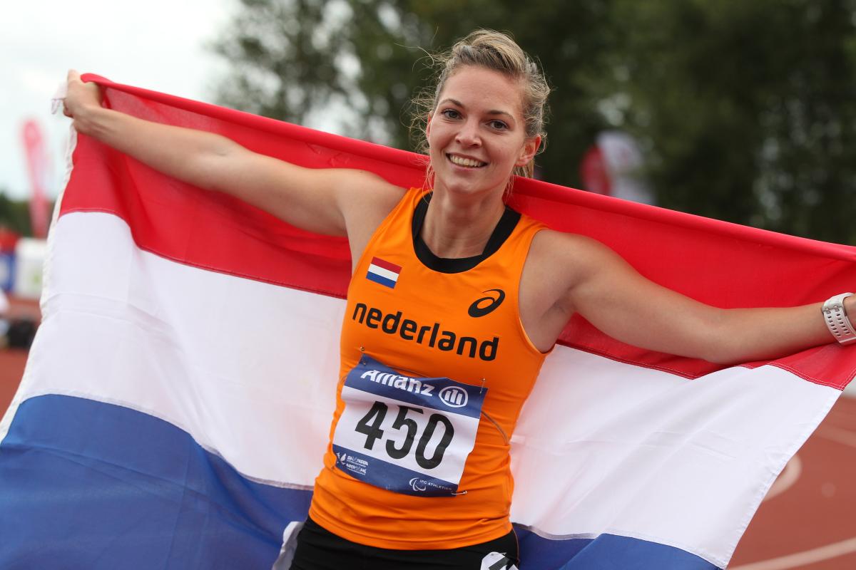 Women with a Dutch flag smiles to the camera
