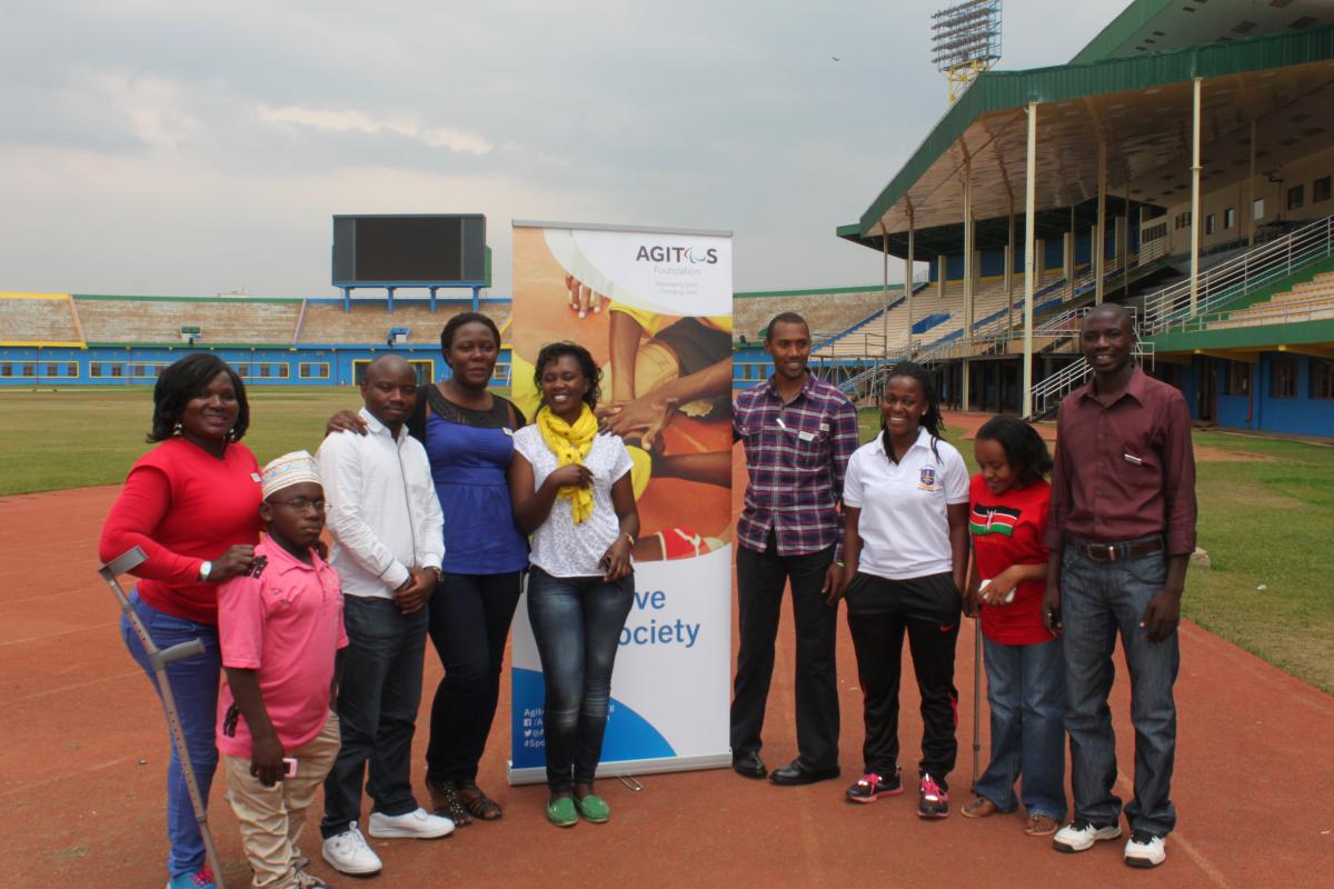 A group of people pose in front of an Agitos Foundation pull-up