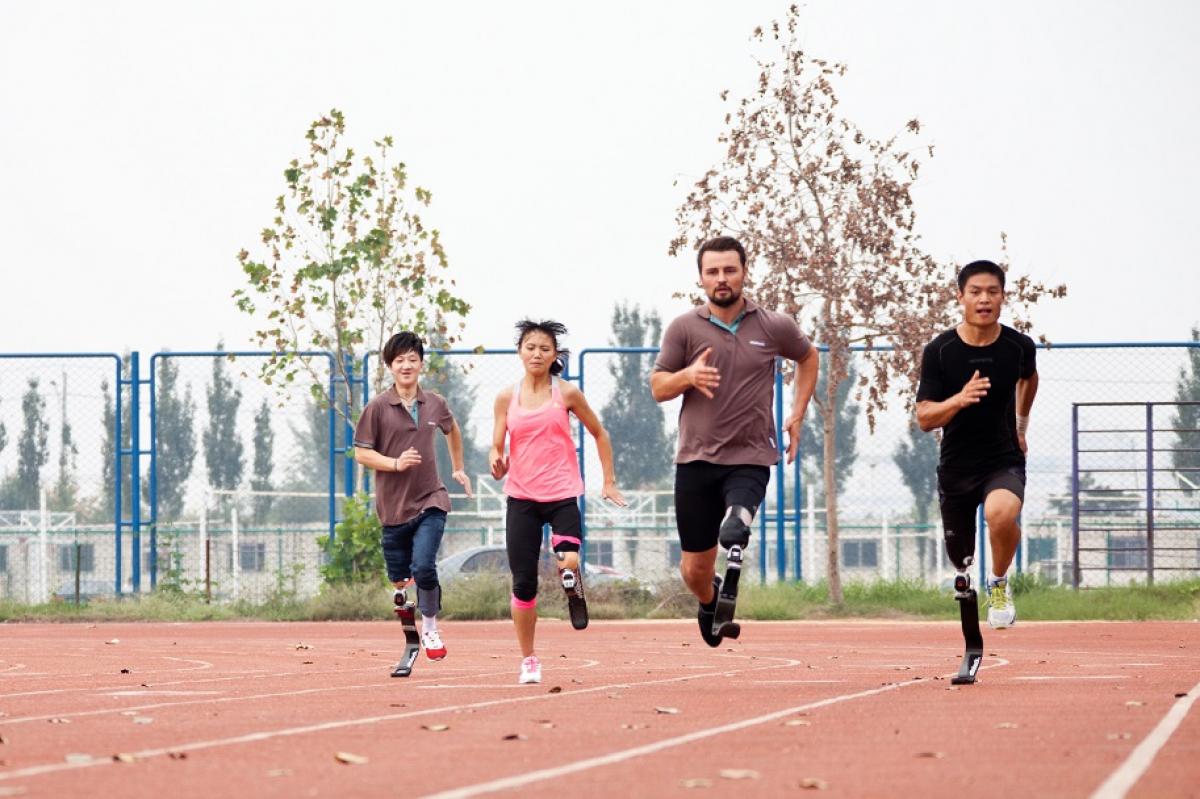 Four people with prothesis sprinting