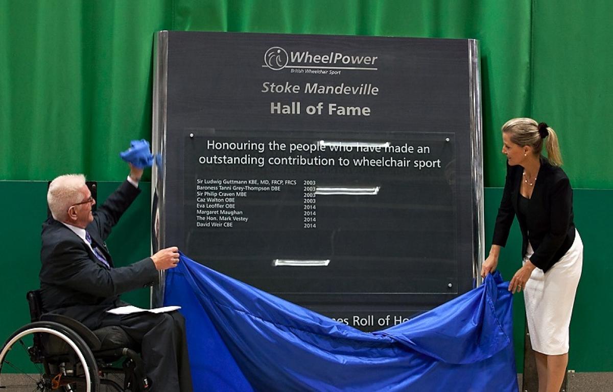 Stoke Mandeville Hall of Fame unveiling One women and one man in a wheelchair pull a curtain off a wall.