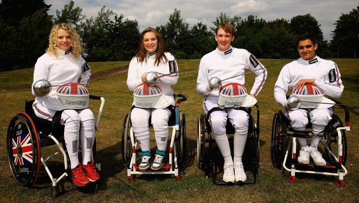 British fencing team Four people in fencing suits and wheelchairs pose with their foils/epees