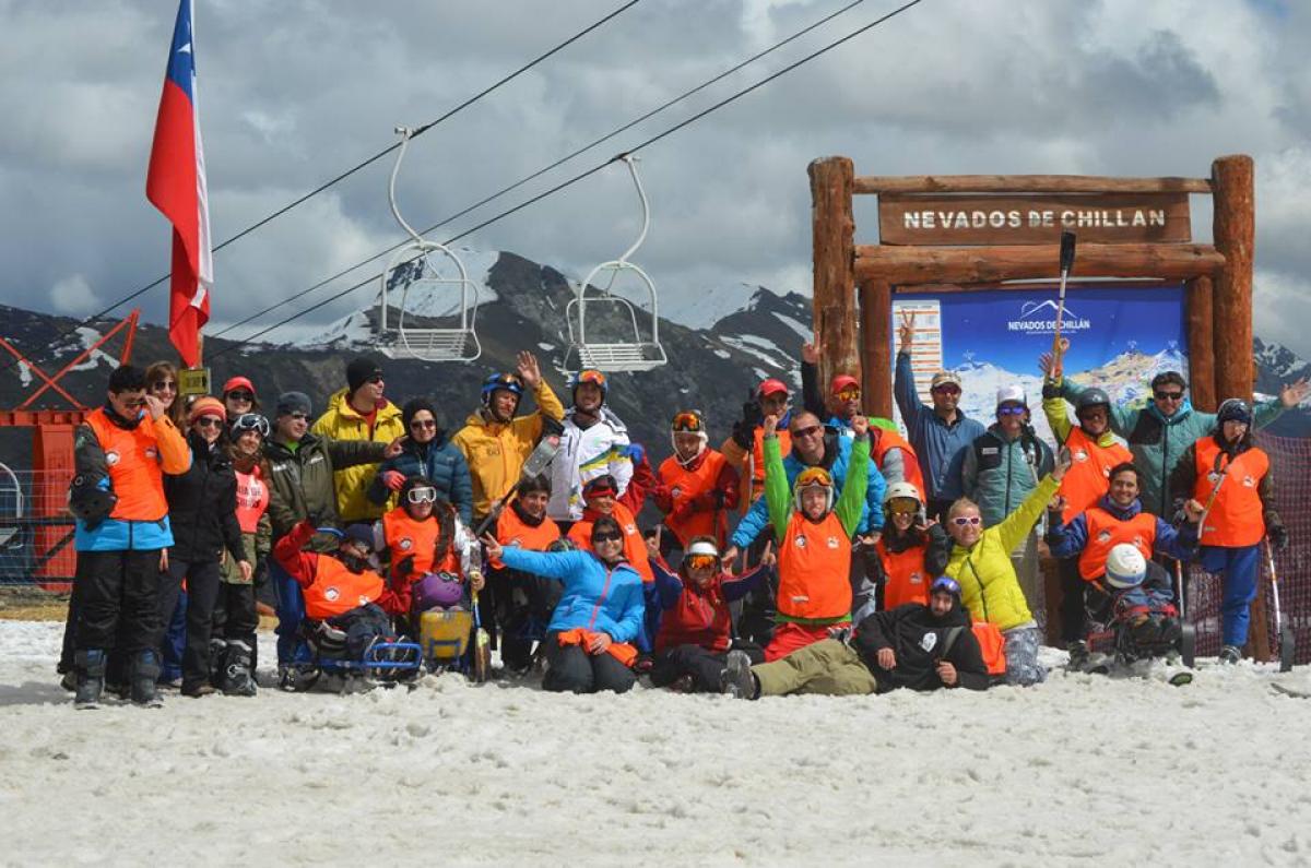 Group of skiers with different impairments in front of a sign saying "Nevados de Chillan"