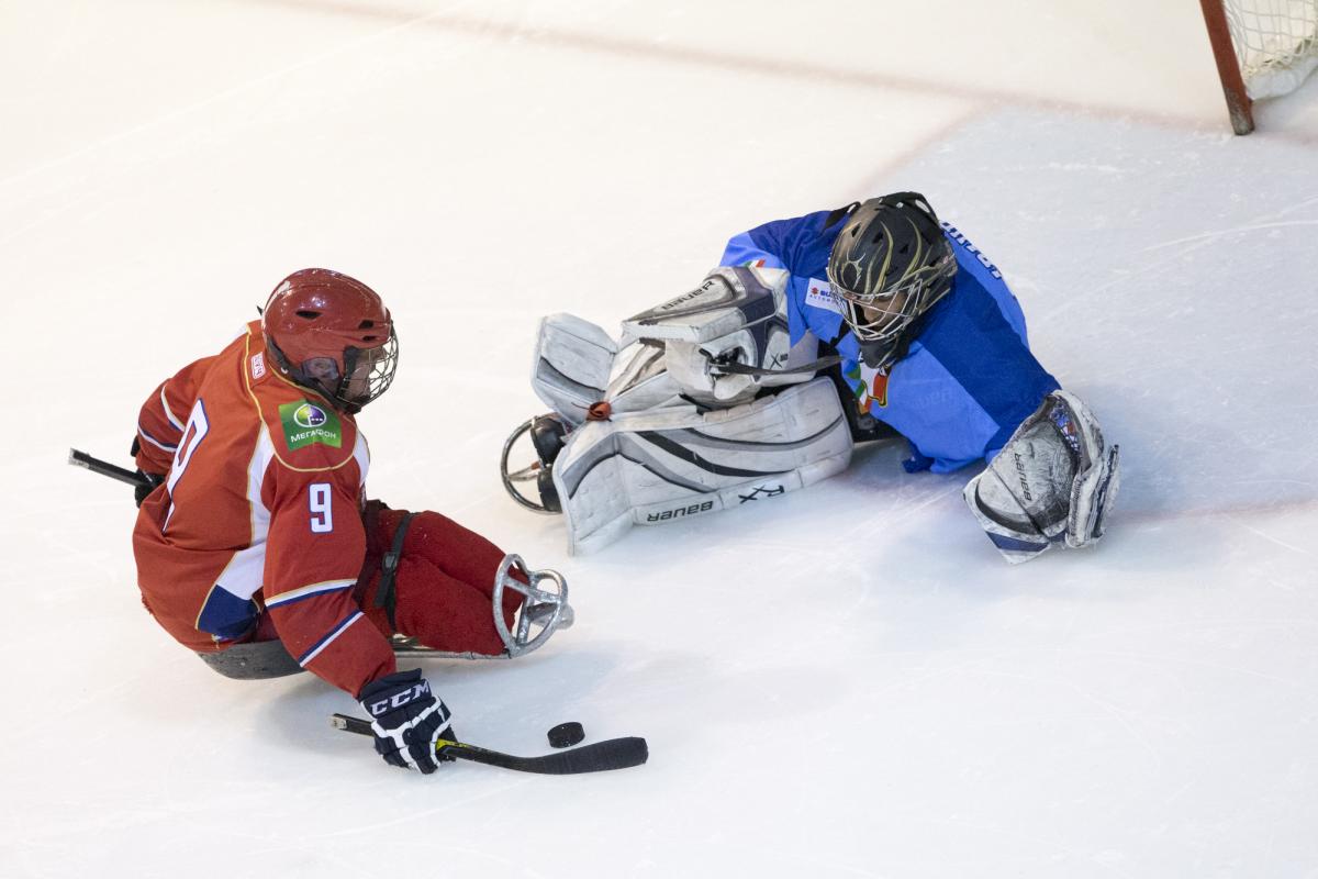 Ice Sledge Hockey player and goalkeeper face each other in a match.