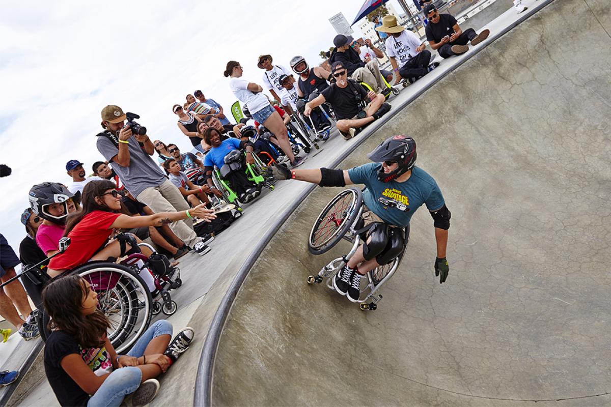 Man in wheelchair doing a stund in a halfpipe