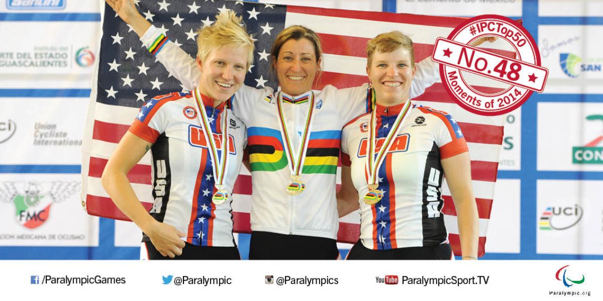 Three women on a podium, smiling to the camera